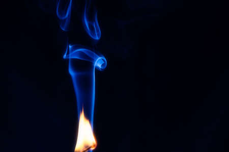 Fire with an abstract figure from blue smoke on a dark background with a place for text, fantasy,fiction, mysticism, magic, copy cpaceの写真素材