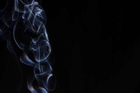 Abstract puffs of smoke on the left side of the frame on a dark background with a place for text, mysticism, fantasy Copy spaceの写真素材