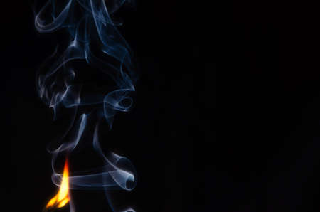 Fire with an abstract figure from blue smoke on a dark background with a place for text, fantasy,fiction, mysticism, magic, copy cpaceの写真素材