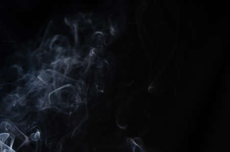 Abstract puffs of smoke on the left side of the frame on a dark background with a place for text, mysticism, fantasy.Copy spaceの写真素材