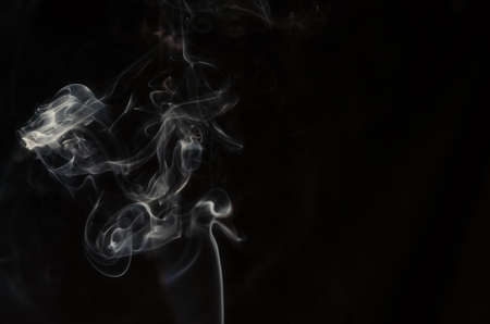 Abstract puffs of smoke on the left side of the frame on a dark background with a place for text, mysticism, fantasy.Copy spaceの写真素材