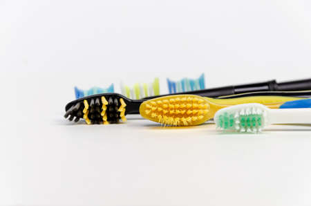 Three colored toothbrushes for the whole family lie on their sides close-up on a white backgroundの写真素材