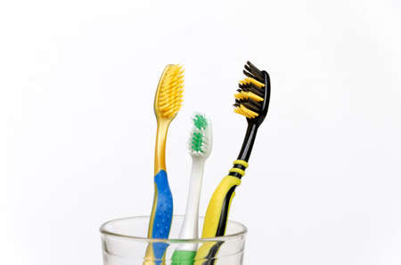 Three toothbrushes for the whole family, for mom, dad, baby in a glass close-up on a white background, dentist day, healthy teeth. Horizontalの写真素材