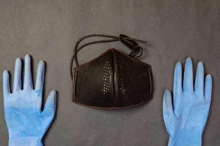 Face mask from dust, chemistry and viruses with rubber blue gloves on a dark background with place for text.の写真素材