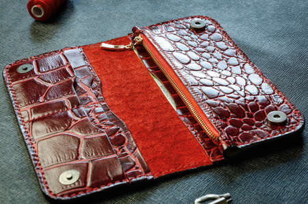 Red womens wallet longer made of genuine crocodile leather, handmade on a dark background. Close-upの写真素材