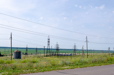 High voltage towers with wires in a green field on a sunny summer day