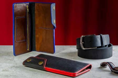 Mens wallet longer made of genuine black leather handmade with a red and blue end on a red backgroundの写真素材