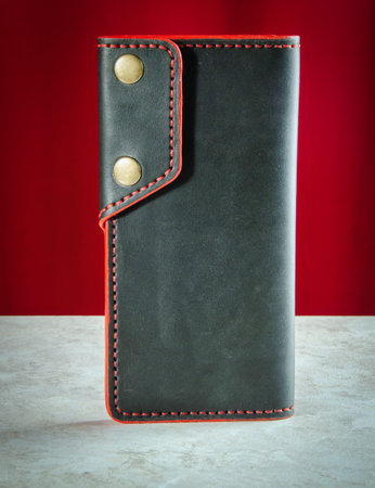 Mens wallet longer made of genuine black leather handmade with a red edge and two buttons close-up