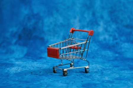 Toy grocery cart on blue background with place for text.の写真素材