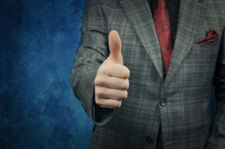 A man in a suit in a cage, with a red tie shows thumbs up.の写真素材