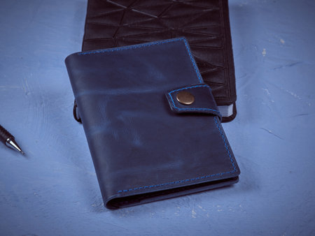 Blue cover for documents made of genuine leather on a black notepad with a pen for writingの写真素材