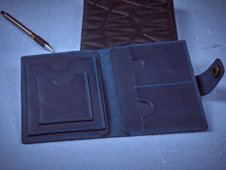 Blue cover for documents made of genuine leather on a black notepad with a pen for writingの写真素材