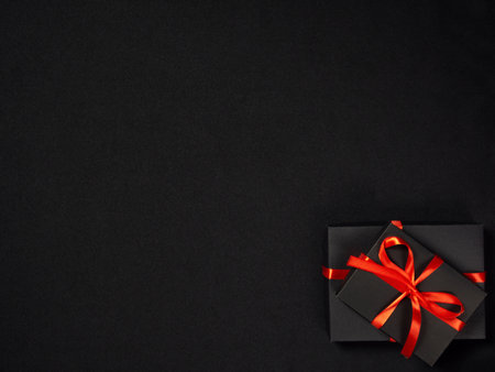 black gift box with red satin ribbon in the corner of the frame on a dark background, space for text, Black Fridayの写真素材