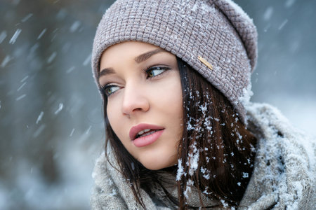 Beautiful young woman in wintertime outdoor, snowfall