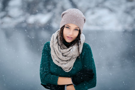 Beautiful young woman in wintertime outdoor. Snowfallの写真素材