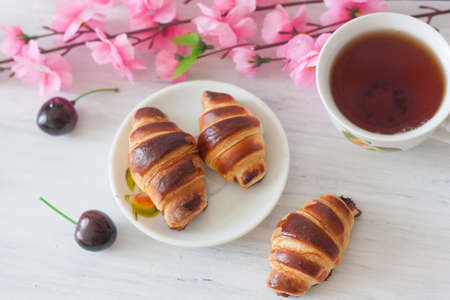 Croissants with cherries and teaの写真素材