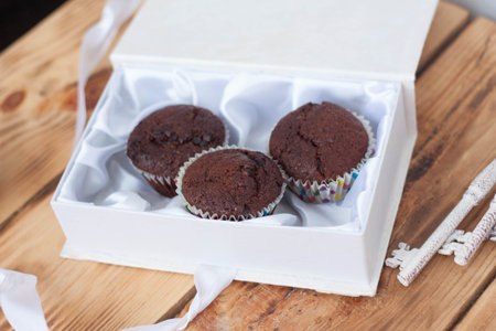 chocolate muffins in a white box on a wooden backgroundの写真素材