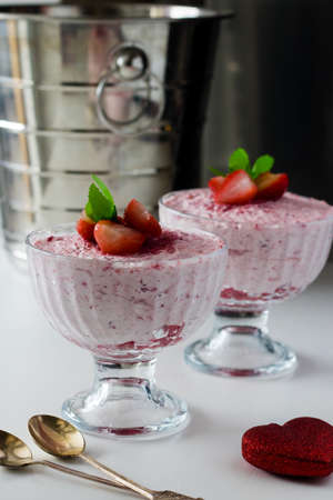 Strawberry mousse in a glass dish decorated with strawberry and lemon balm.の写真素材