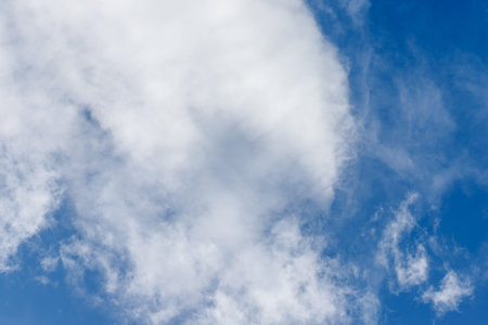 A bright blue sky is partially covered by puffy, white clouds in a high angle shot.