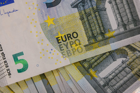 Close-up of multiple 5 Euro banknotes, with details of the design including the number, stars, and...