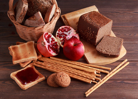 Different buns of fresh bread and spikelets of wheat on a brown vintage background
