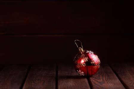 Christmas New Year decoration. Red vintage ball with golden on wooden table dark wooden background side viewの写真素材