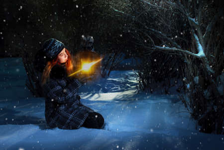 pretty redhead girl holding lantern in winter forestの写真素材