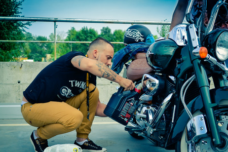 Man changes the oil in Motorcycles. Motorbike Harley Davidson under blue sky, july 15, 2015. Kiev, festival USA in Ukraineのeditorial素材
