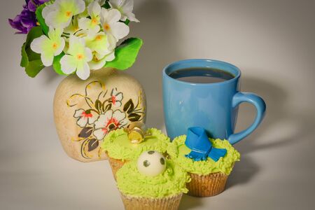 Hot coffee with cakes near the vase with flowersの写真素材