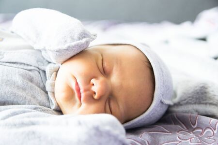 Beautiful newborn sweetly sleeps in the crib and has beautiful dreamsの写真素材