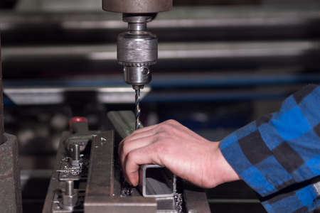 a man in a blue shirt drills a hole in the detailsの写真素材