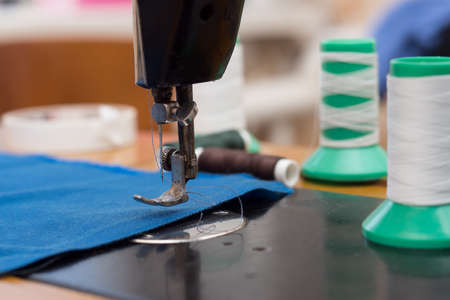 The old sewing machine is sewn blue cloth in the home workshopの写真素材