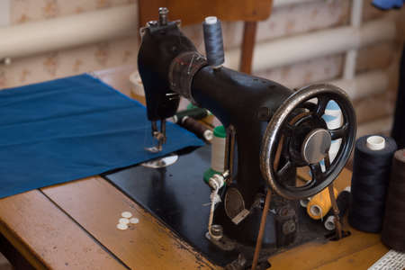 The old sewing machine is sewn blue cloth in the home workshopの写真素材