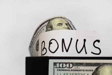 The inscription Bonus, gift package with dollars on the table on a white backgroundの写真素材