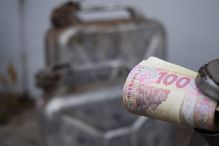 Metal barrel and Ukrainian money, the concept of the cost of gasoline, diesel, gas. Refilling the...