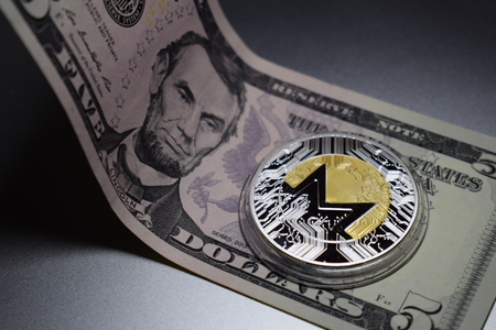 Monero cryptocurrency coin on a five dollar bill. Digital money.の写真素材
