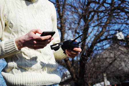 Remote control and smartphone in male hands. A man holding a transmitter and piloting some vehicles....