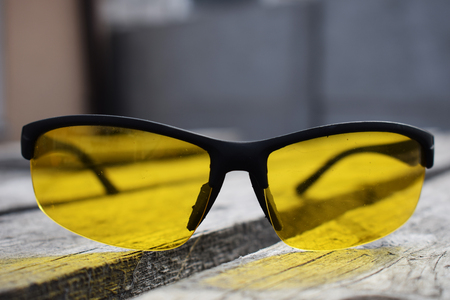 Yellow glasses on a wooden background. Glasses lie. Black orange glasses .の写真素材