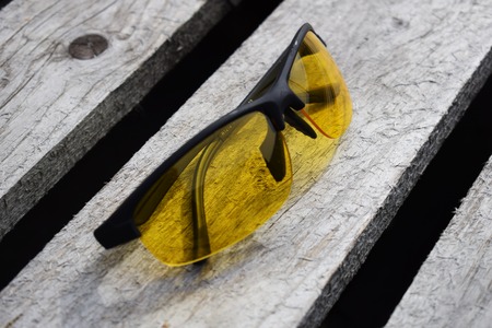 Yellow glasses on a wooden background. Glasses lie. Black orange glasses .の写真素材