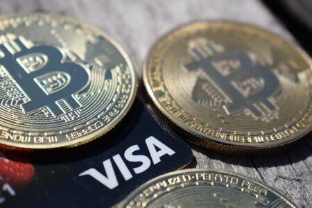 Ukraine, Kremenchug - March, 2019 Golden Bitcoins on Visa Card on wooden background.のeditorial素材