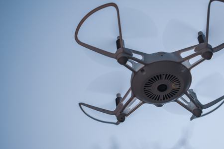 Quadcopter drone hovering in a blue skyの写真素材