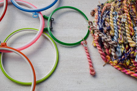 Multicolored embroidery hoops for creative art and threads of floss braided threads for embroidery on a light background.の写真素材