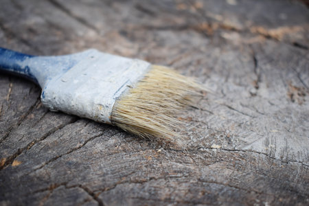 Brush on a wooden background. Painting wooden surface. Old brush. Gray paint.