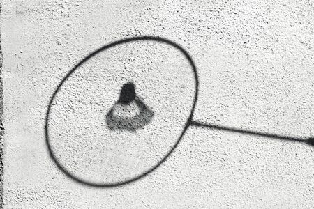 Shadow of a badminton racket against a white wall. Sport concept. Creative copyspaceの写真素材