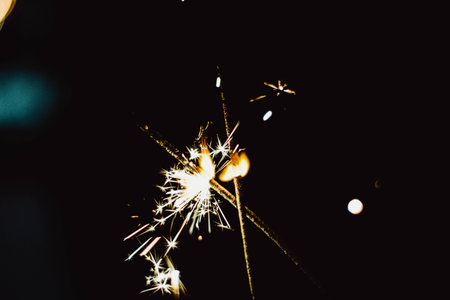 Glittering burning sparkler, abstract blur background.
