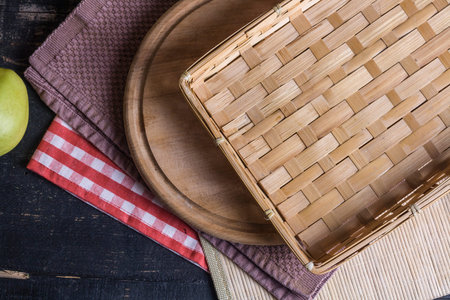 Wicker basket and napkin on dark wooden background, top viewの写真素材