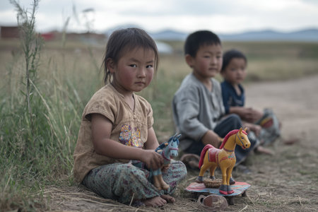 Little girl and boy playing with wooden horse toy in the field.の素材