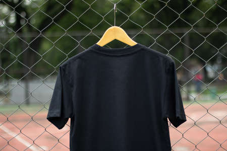 Blank black t-shirt on wood hanger in outdoor. Ready for your mock up design or presentation your design project.の写真素材