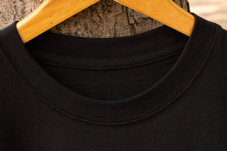 Blank black t-shirt on wood hanger in outdoor. Ready for your mock up design or presentation your...