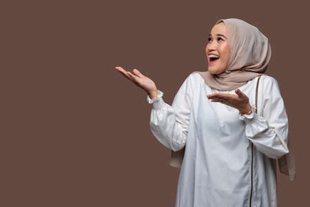 Beautiful woman in hijab is holding a mobile phone and showing it forwardの写真素材